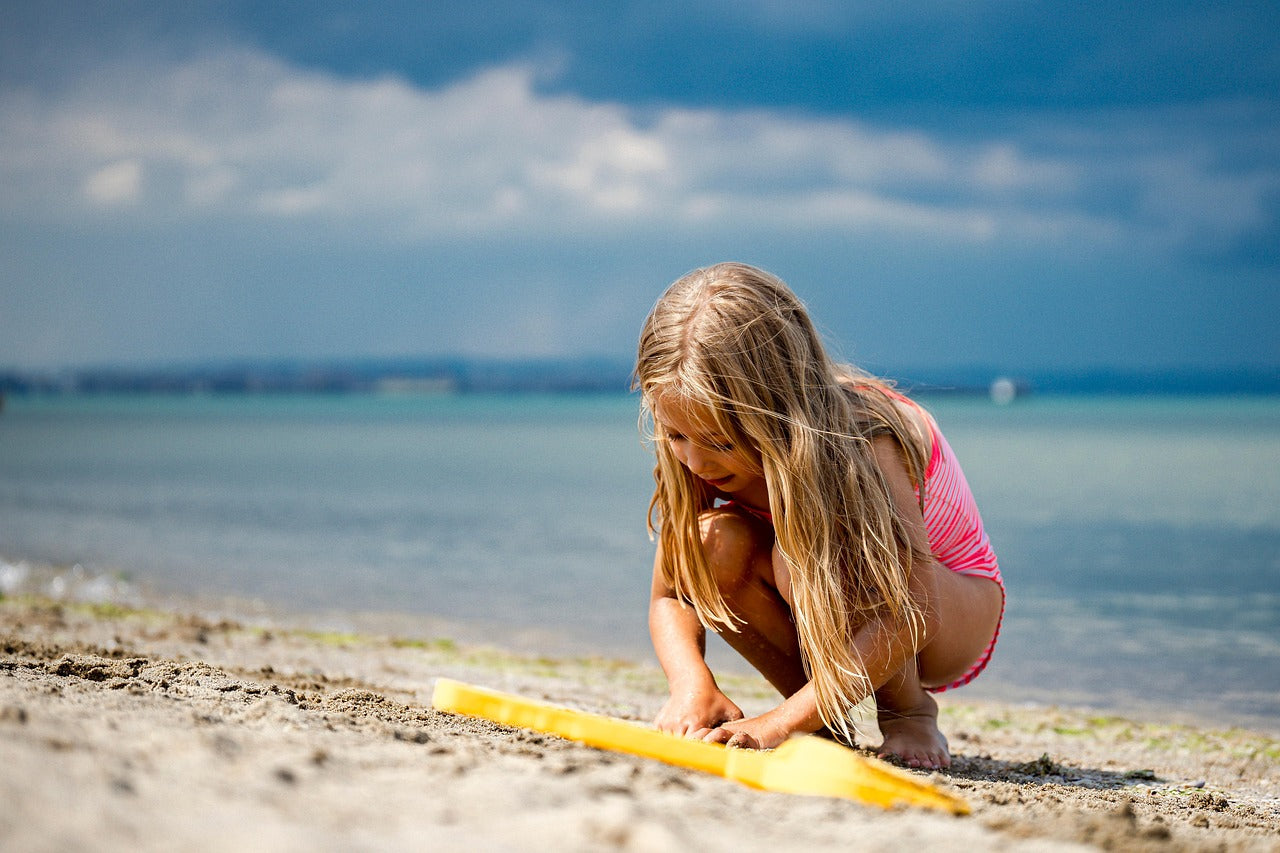 A little girl is playing with her toys on the beach.